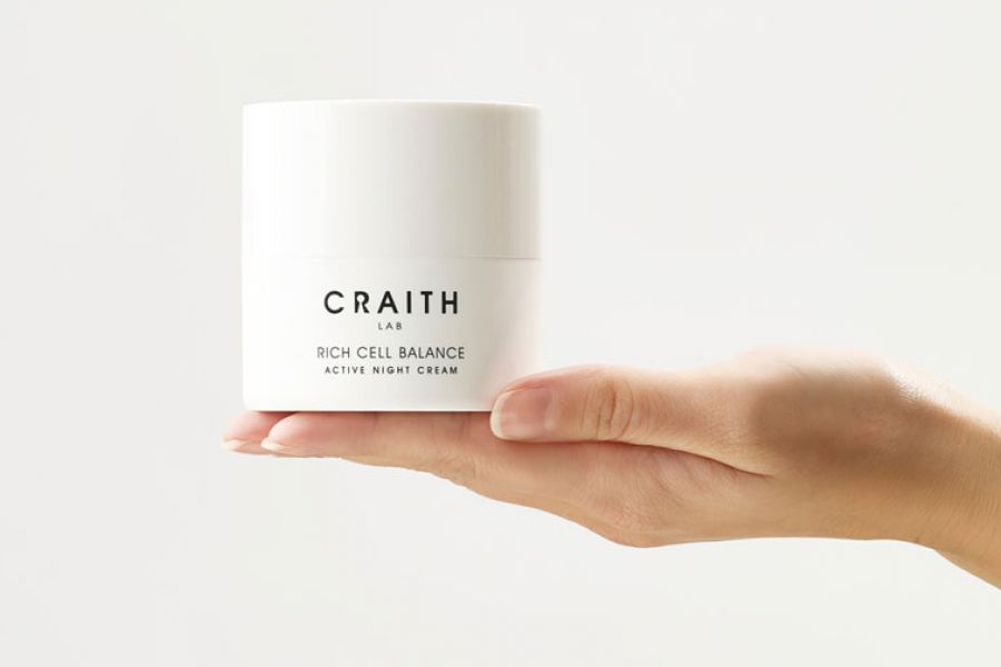 Weiße Cremedose auf einer ausgestreckten Hand.